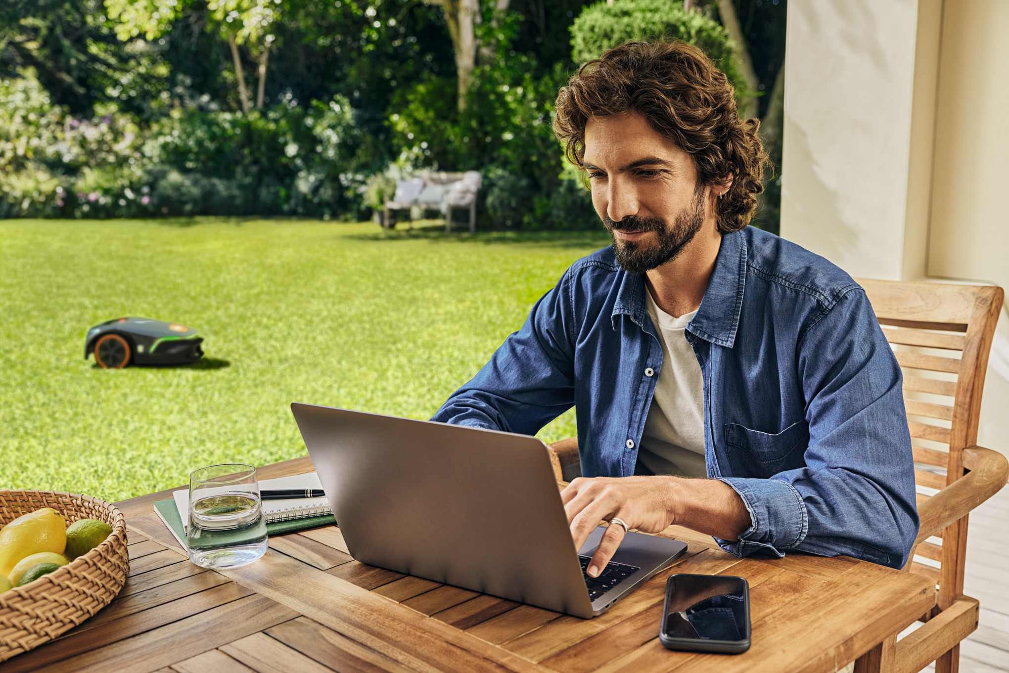 A man works on his laptop in the garden.