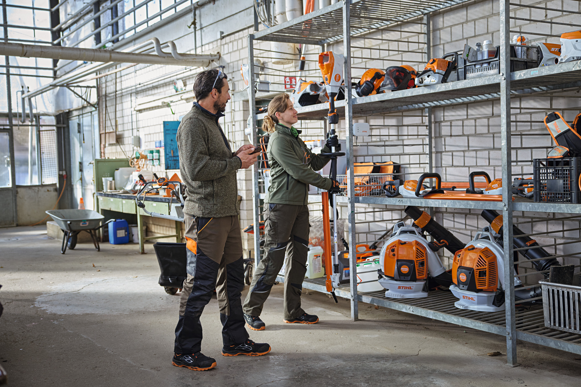 Landcaping professionals in a storage room check the product status using the STIHL connected app