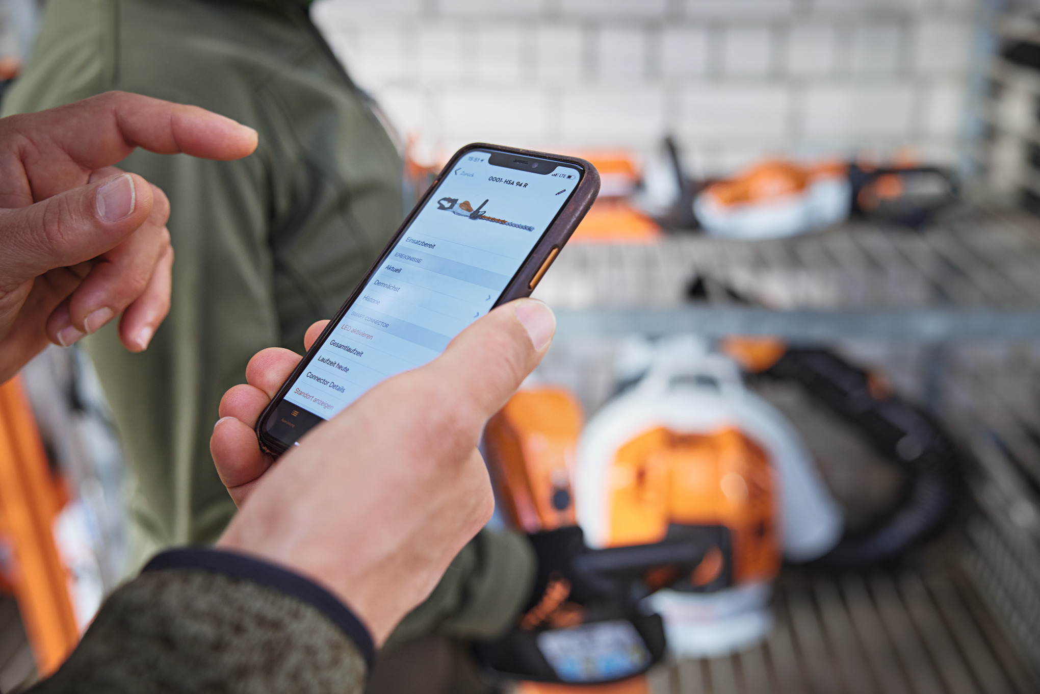 A person with a smartphone looking at a chainsaw in the STIHL connected App